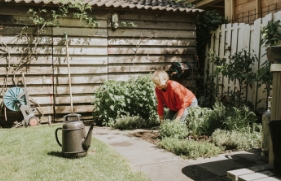 Een vrouw werkt op een zonnige dag in de tuin.