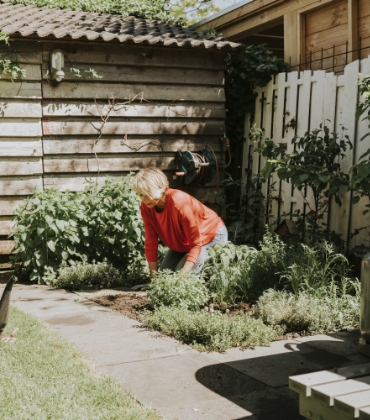 Een vrouw werkt op een zonnige dag in de tuin.