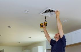 Man bevestigt ventilatierooster in een plafond
