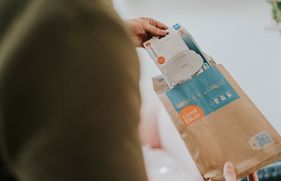 Iemand haalt een rookmelder uit de verpakking. Lees waar je op let als je een rookmelder koopt.