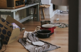 Pannen en handdoeken vangen water op wat lekt, op een laminaatvloer