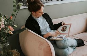 Een vrouw zit op de bank een boek te lezen